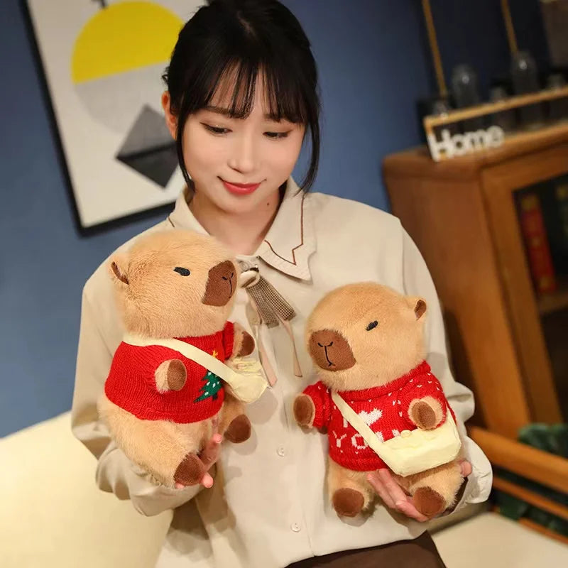 Woman holding two small kawaii teddy bears wearing red sweaters in a room.