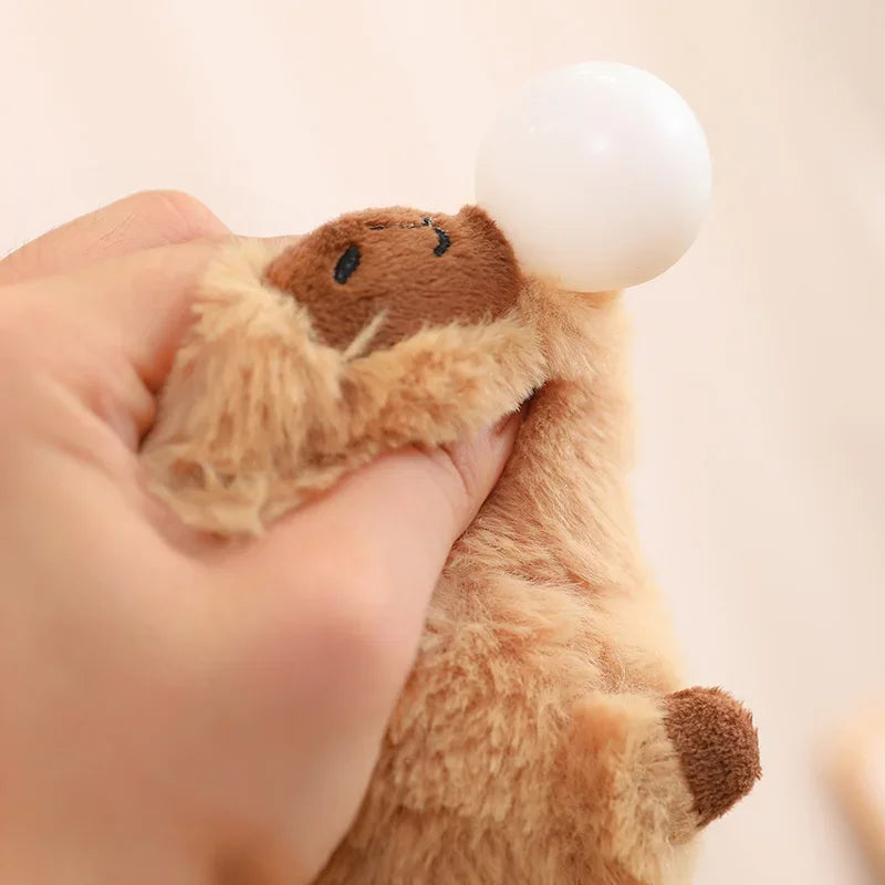 Plush toy resembling a kawaii bear with a white ball on its head, held by a hand against a neutral background.