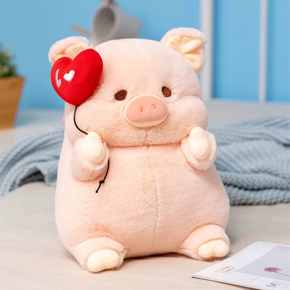 Cute plush pig toy with a red heart on a bed