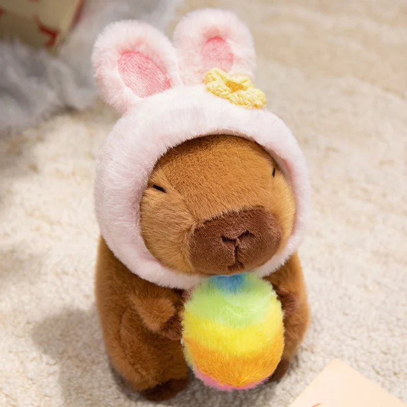 Kawaii plush toy bear wearing a bunny hat with a rainbow ball on a soft surface