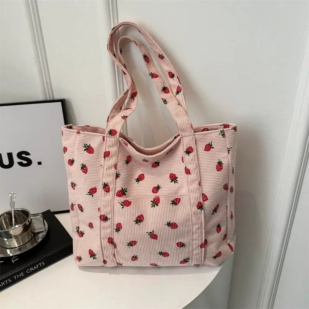 Pink tote bag with strawberry pattern on a white surface