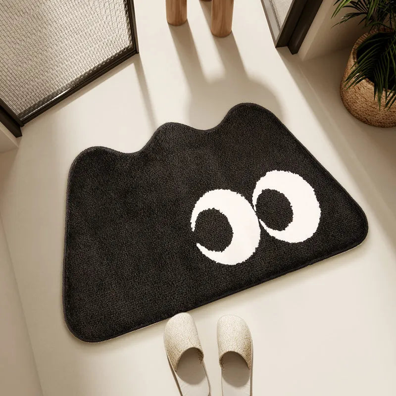 Black kawaii rug with white eye design on a light wooden floor.
