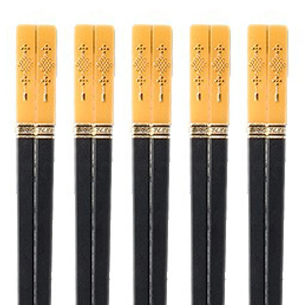 Five pairs of black kawaii chopsticks with yellow tips on a white background