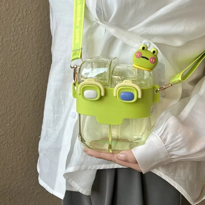 Clear kawaii water bottle with green frog-shaped lid held by a person wearing a white shirt.