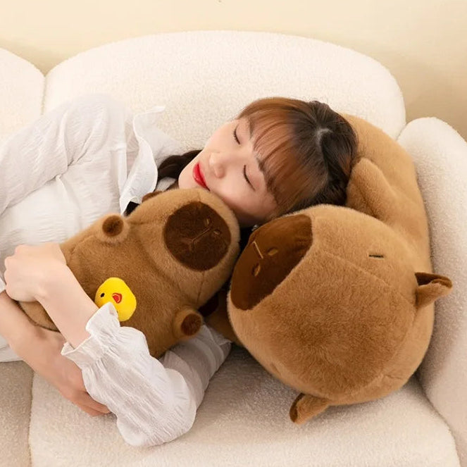 Person lying on a couch with a large brown kawaii plush toy, surrounded by soft text and graphics.