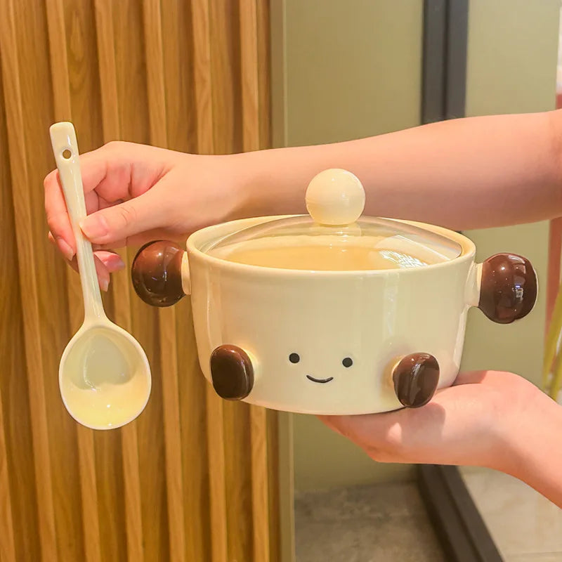 Cute ceramic kawaii bowl with a face design held by a person, accompanied by a spoon.