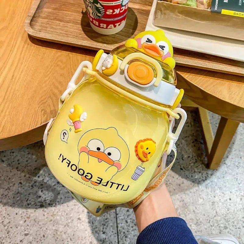 Yellow duck-shaped kawaii water bottle with cartoon design on a wooden table.