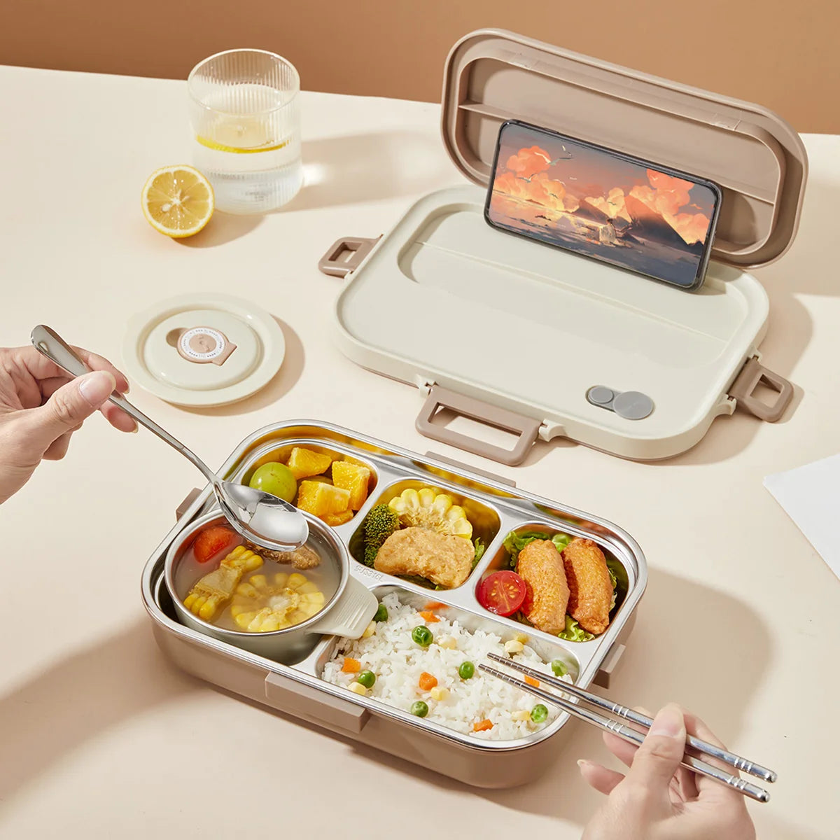 Kawaii lunch box with compartments containing food, a phone on top, and a hand using chopsticks.