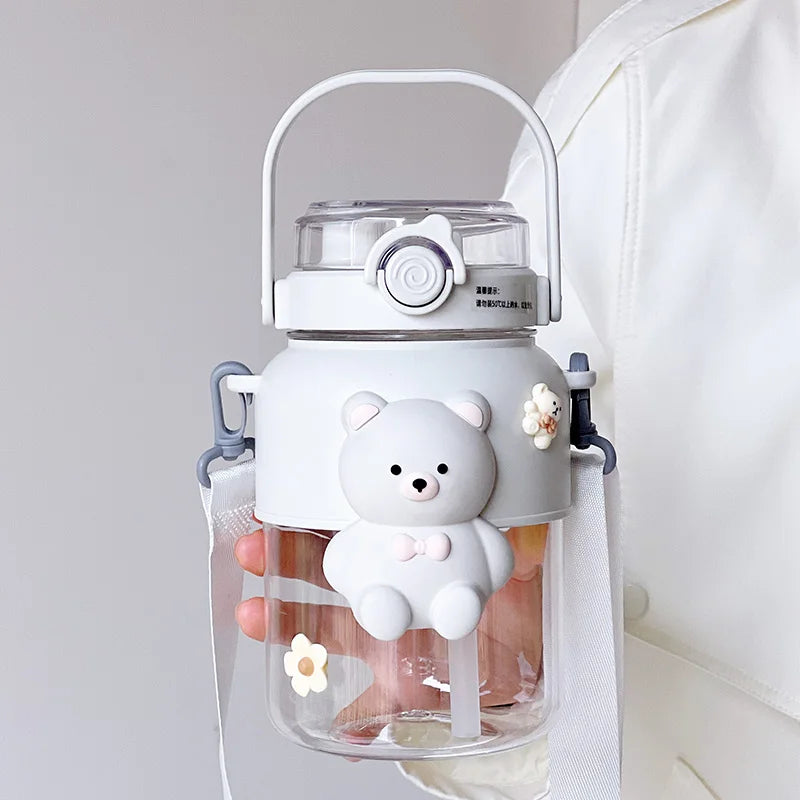 Clear kawaii water bottle with a bear-shaped handle and lid, held by a person.