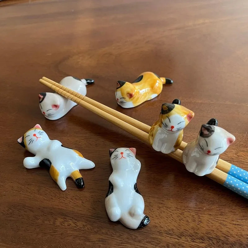 Set of cat-shaped ceramic kawaii chopstick holder on a wooden surface