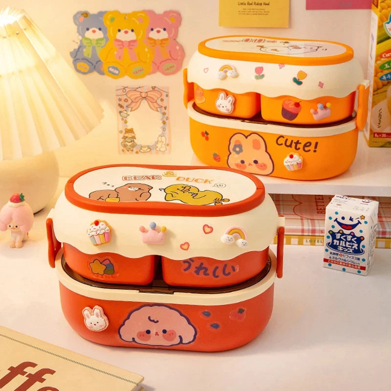 Two cartoon-themed kawaii lunch boxes on a desk with stationery items.