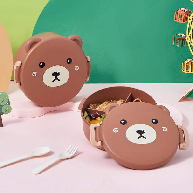 Bear-shaped kawaii lunch box with food on a pink surface with a green background