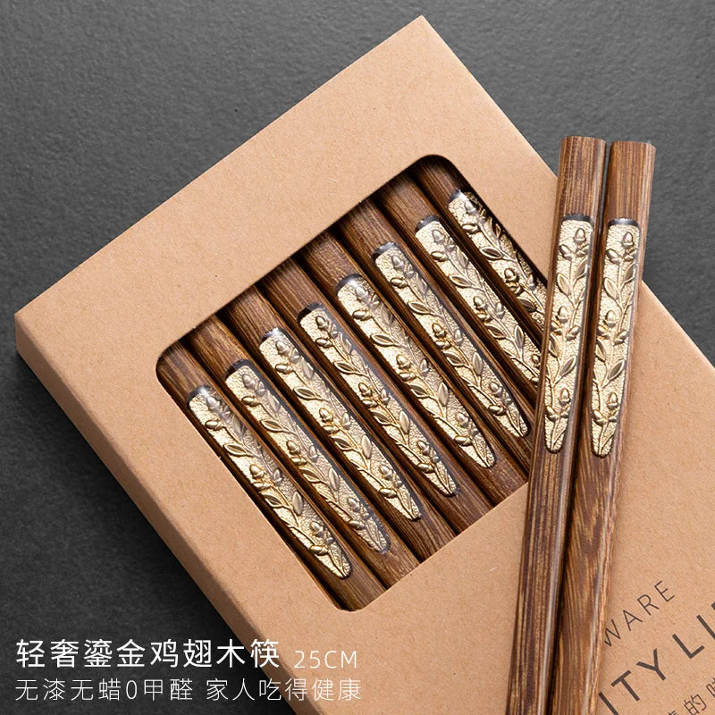 Set of wooden kawaii chopsticks with gold accents in a brown box on a dark background
