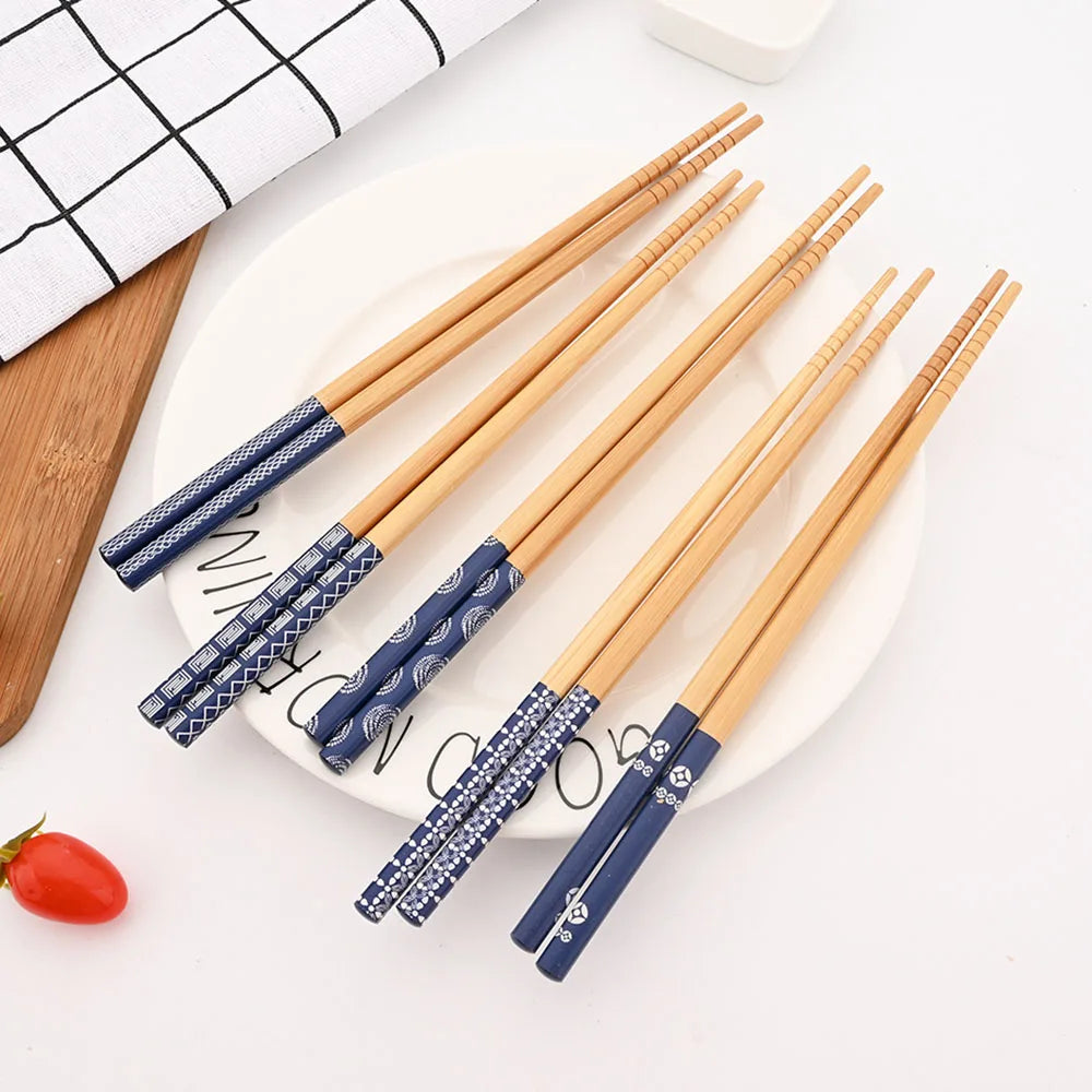 Set of wooden kawaii chopsticks with blue decorative handles on a white plate.