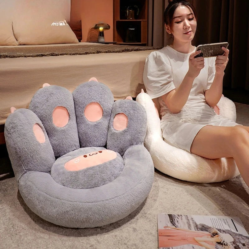 Woman sitting on a paw-shaped kawaii cushion in a cozy room.