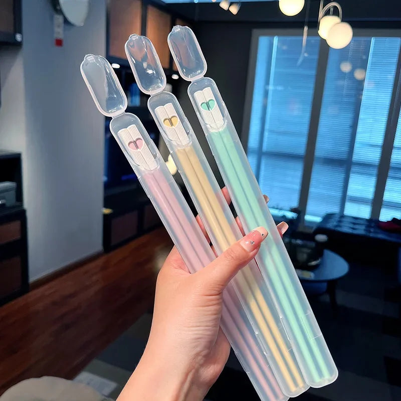 Hand holding four kawaii chopsticks with colorful designs in a living room setting