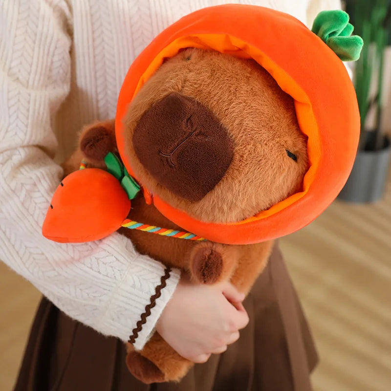 Kawaii plush toy bear in a pumpkin costume held by a person wearing a white sweater.