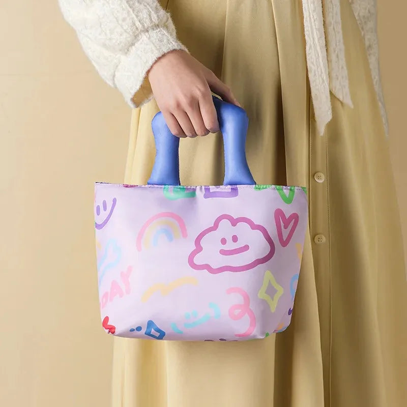 Person holding a colorful kawaii tote bag with rainbow and cloud patterns against a beige background