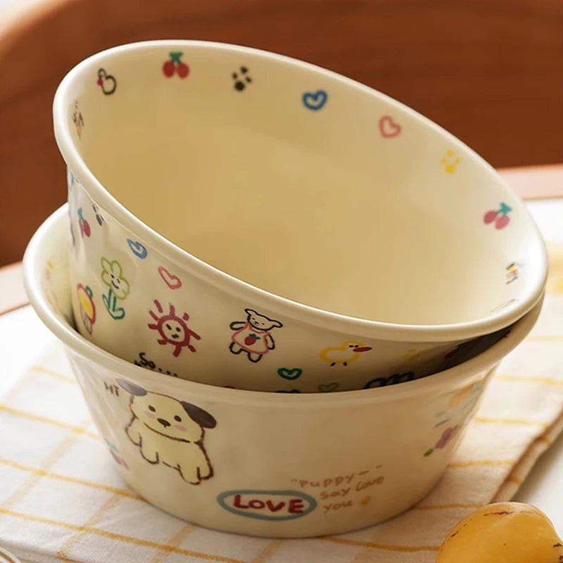 Two ceramic kawaii ramen bowls with colorful illustrations on a checkered tablecloth.