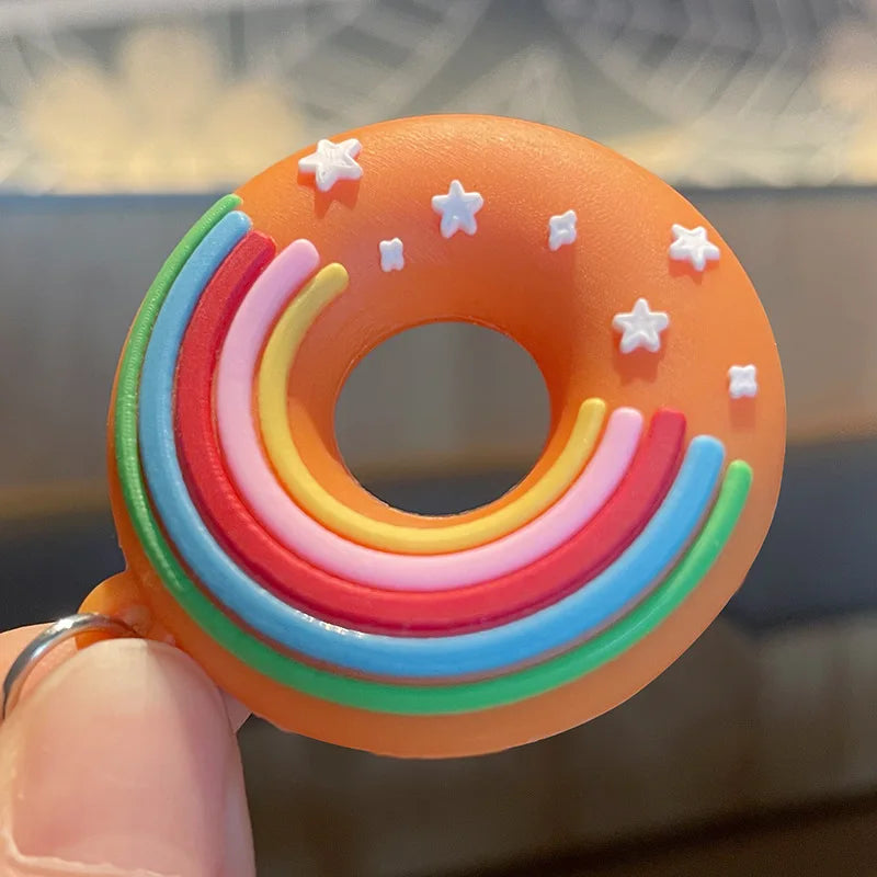 Colorful kawaii donut-shaped object with star decorations held by a hand against a blurred background