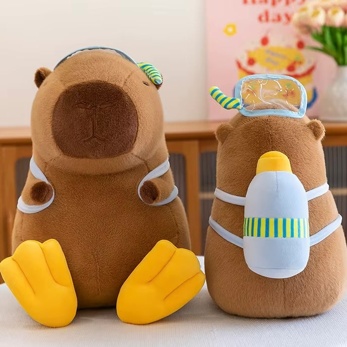 Two brown capybara plush toys wearing swimwear accessories, including a swim cap, goggles, a swim tail, and a floating swim bottle, displayed side by side.