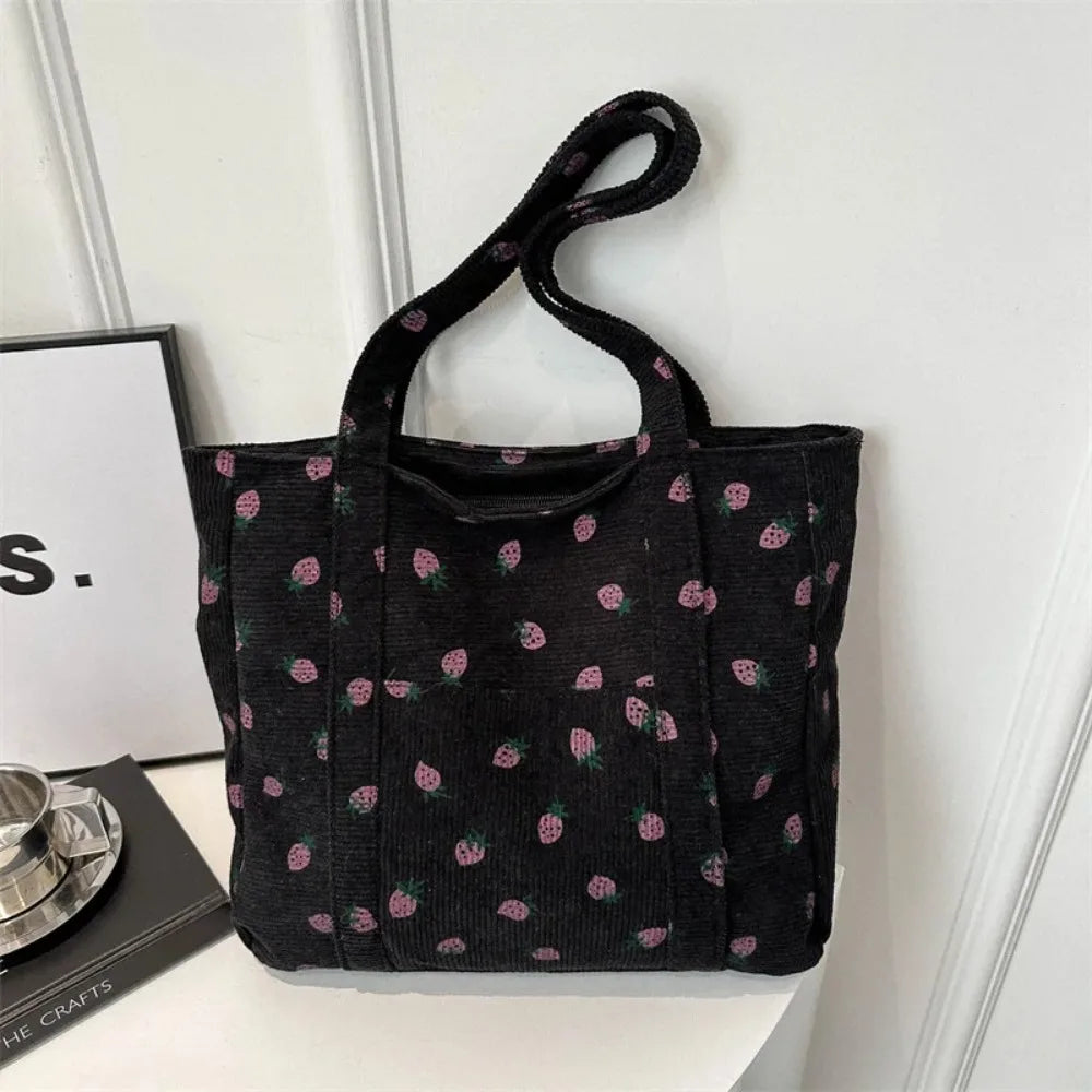 Black tote bag with pink floral pattern on a white surface