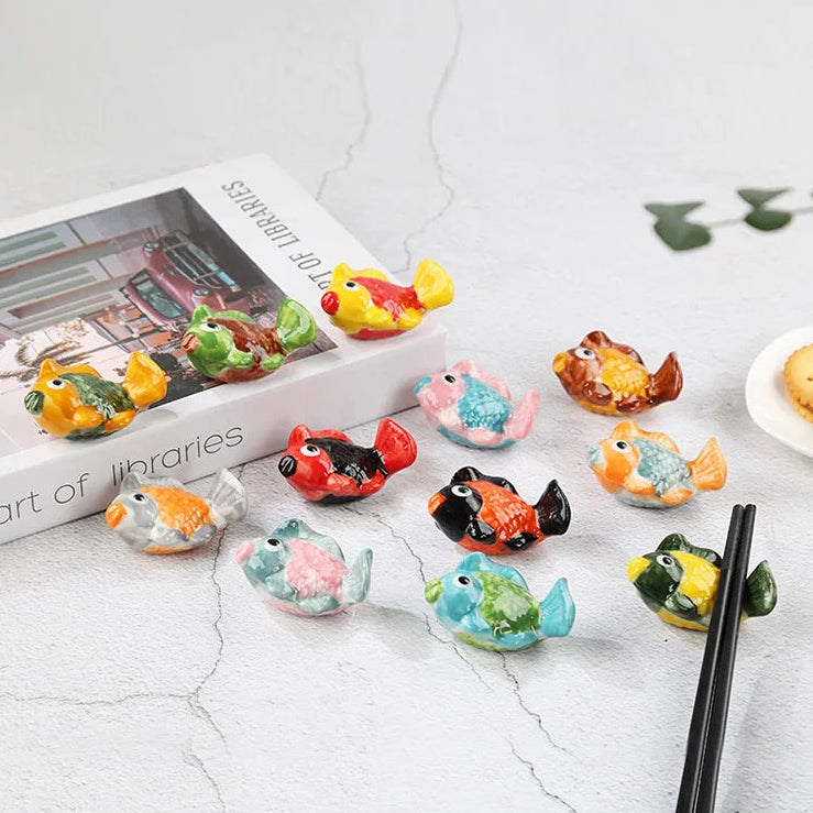 Cherry kawaii chopstick holders with colorful fish-shaped holders on a white surface.