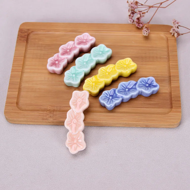 Colorful flower-shaped kawaii chopstick holders on a wooden board with a light background