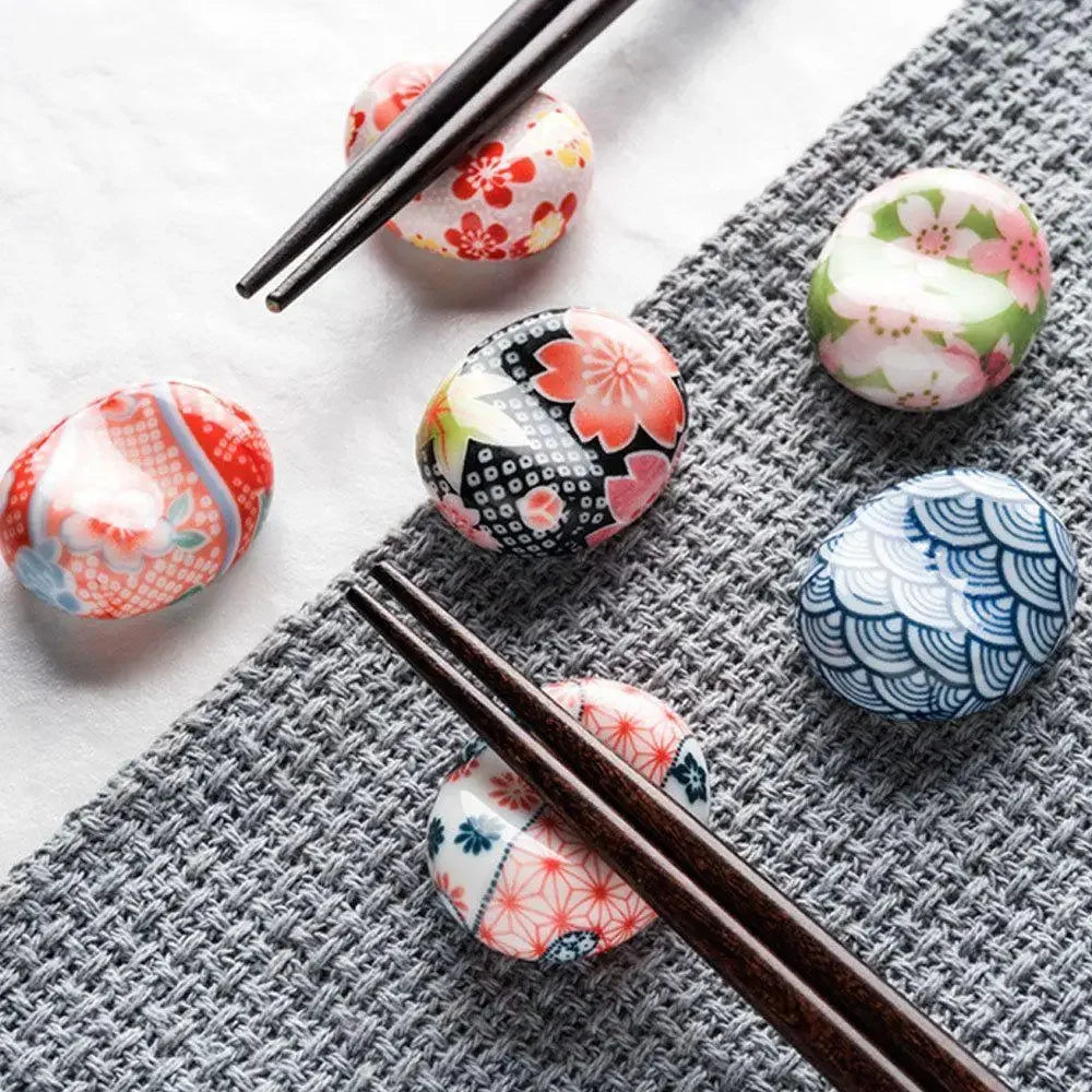 Decorative kawaii chopstick holders with floral patterns and chopsticks on a textured surface