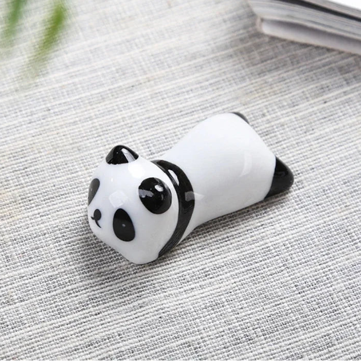 Panda-shaped kawaii chopstick holders on a textured surface