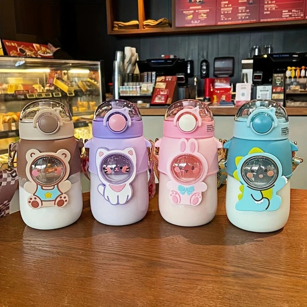 Four cartoon-themed kawaii water bottles on a counter in a cafe setting.