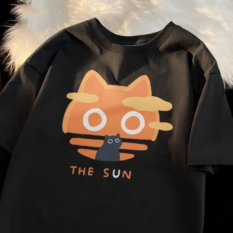 Black t-shirt with a kawaii cartoon cat design and text 'THE SUN' on a fluffy white background