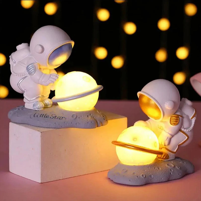 Two astronaut kawaii night lights with glowing orbs on a dark background with string lights.