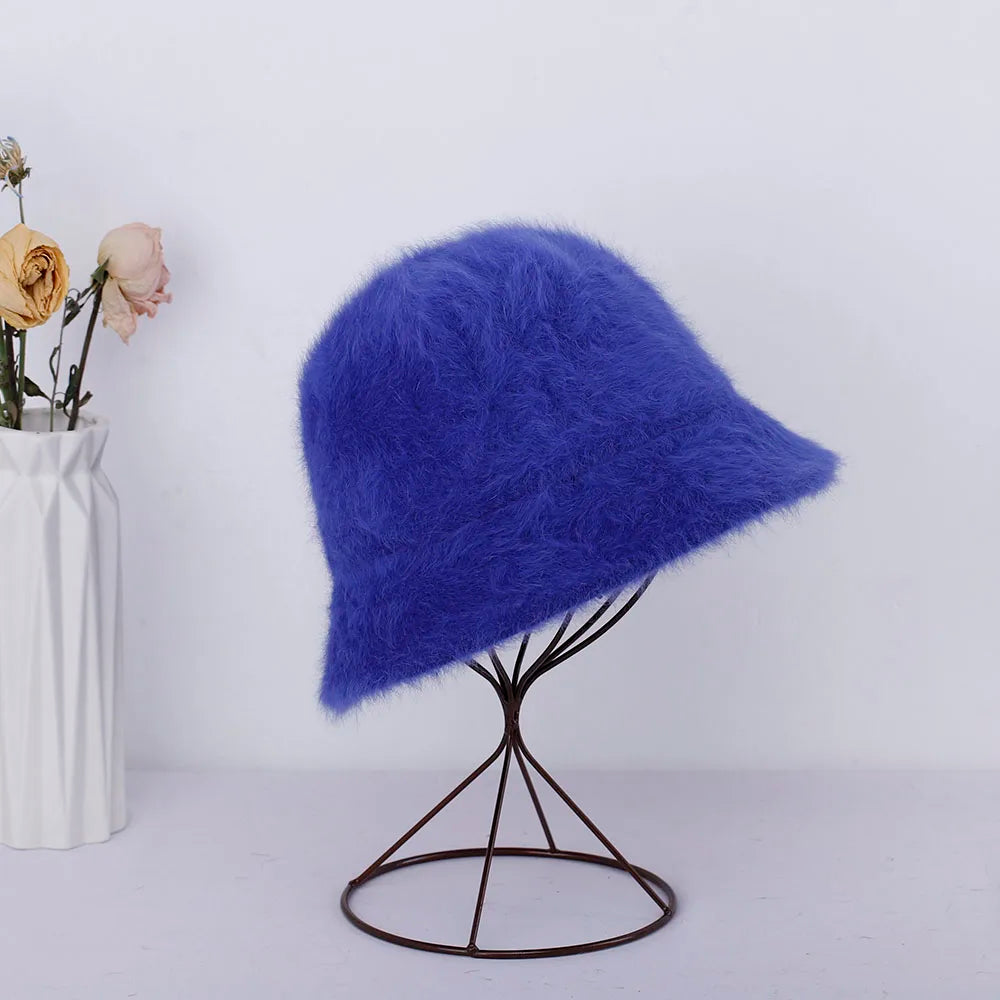 Blue fluffy Kawaii hat on a black stand with a white vase containing flowers on a light gray background