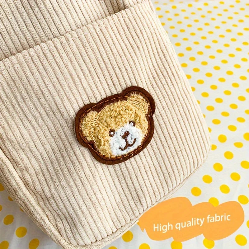 Close-up of a cream-colored ribbed corduroy fabric item featuring a teddy bear face patch, set against a white background with yellow polka dots and an orange 'High quality fabric' badge.