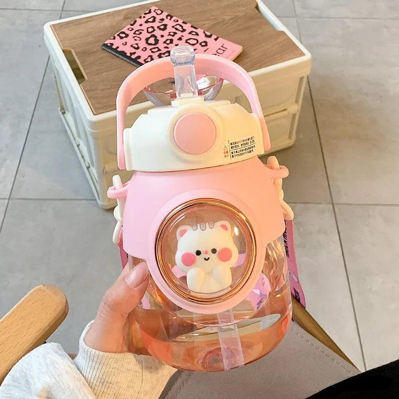 Pink and clear kawaii water bottle with a bear charm held by a person indoors.