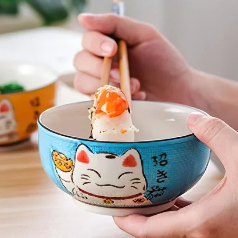 Person holding a kawaii bowl with a cat design, eating food with chopsticks.