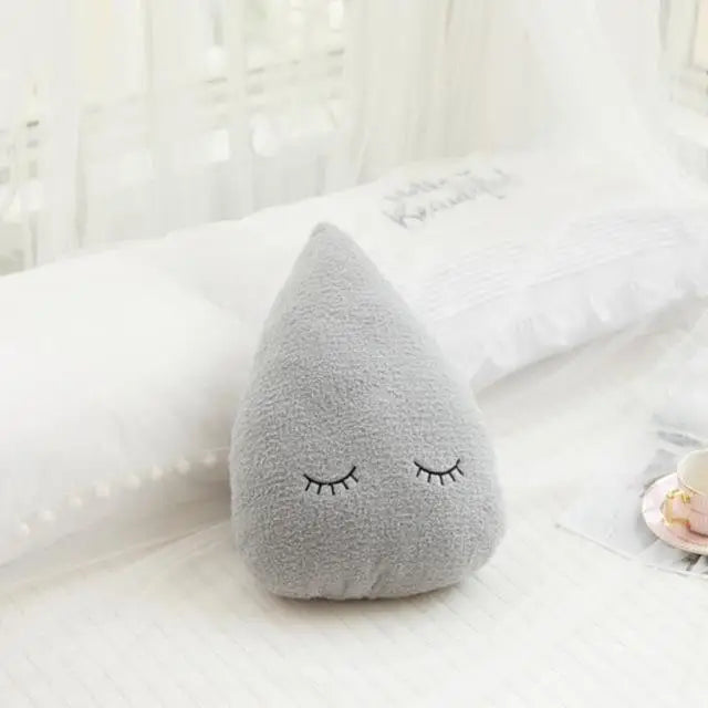 Gray teardrop-shaped kawaii cushion with a face on a white surface