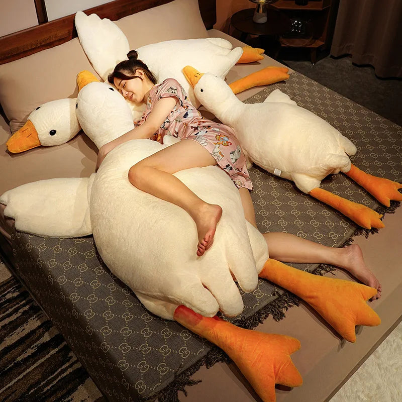 Child lying on a large white goose-shaped kawaii pillow on a bed