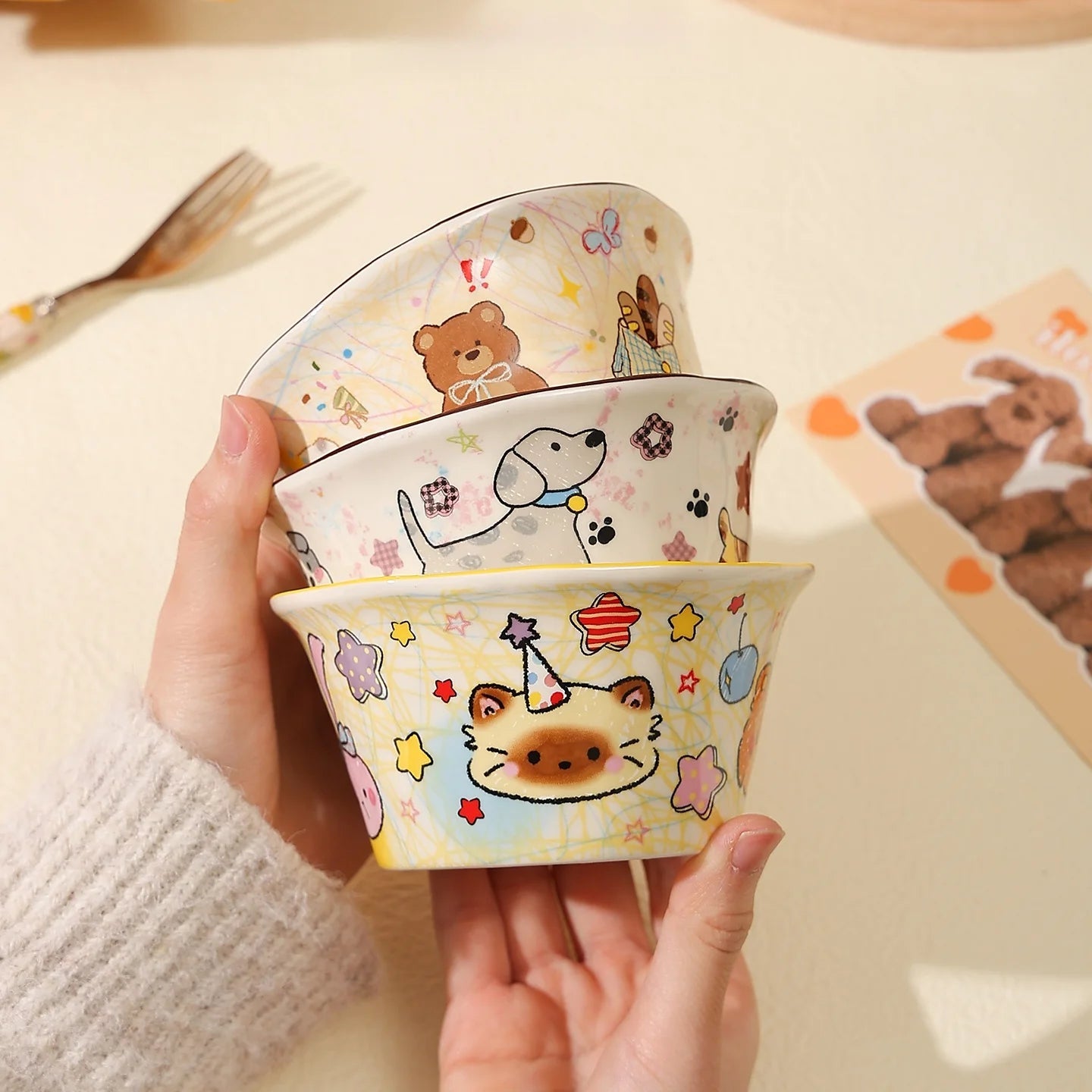Set of cartoon-themed ceramic kawaii ramen bowls held by a person on a light background