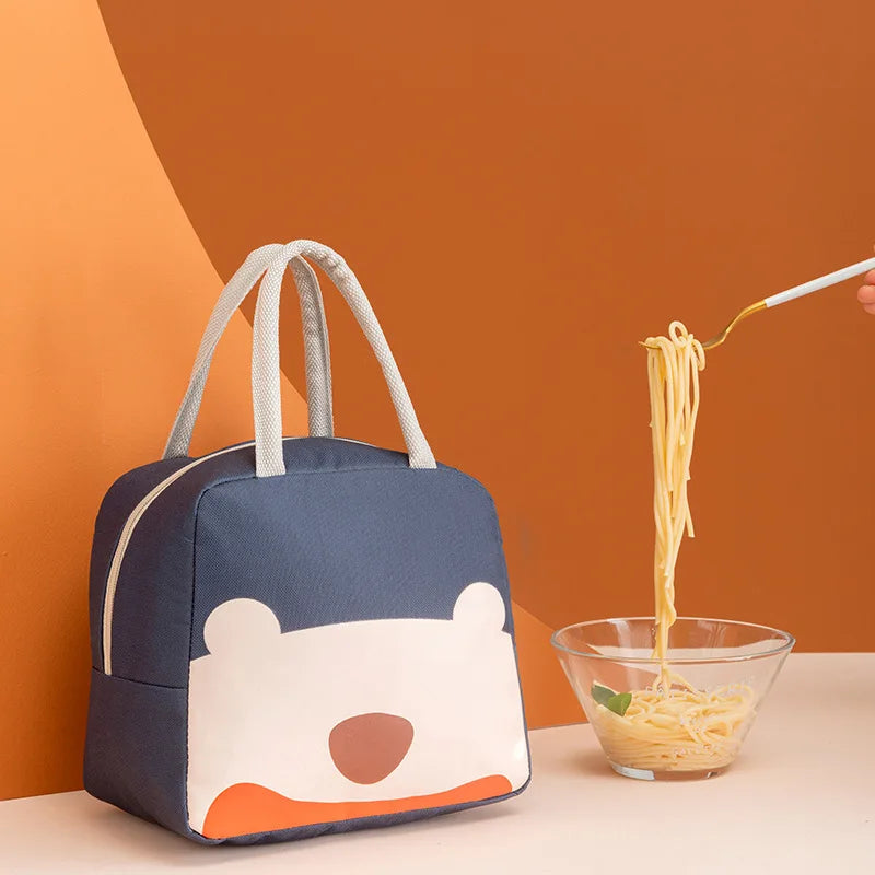 Navy blue kawaii lunch bag with bear design next to a bowl of spaghetti on an orange background