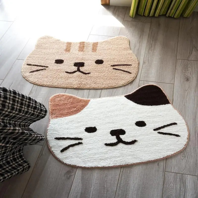 Two cat-shaped kawaii mats on a wooden floor with a checkered cloth.