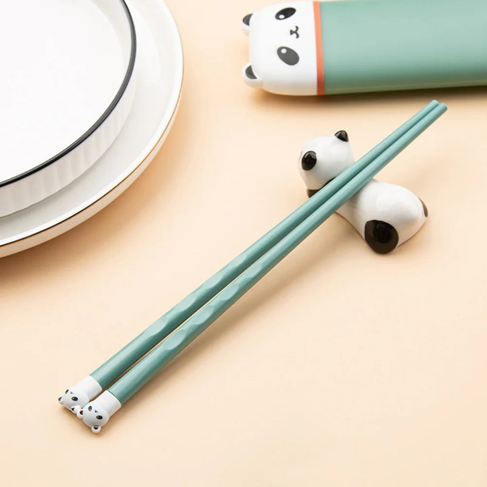 Green kawaii utensils with panda ends on a beige surface