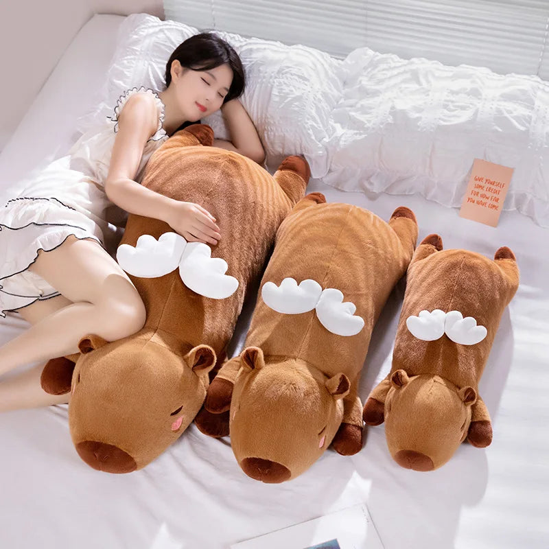 Woman lying on a bed with a large brown kawaii plush toy shaped like a deer.