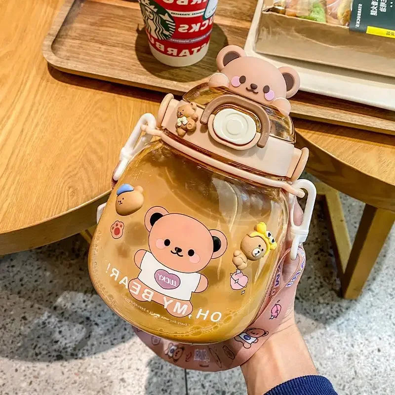 Clear kawaii water bottle with bear design held by a hand on a wooden table.