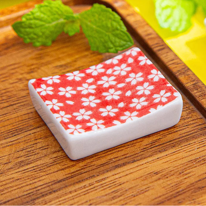 Rectangular kawaii chopstick holders with red and white pattern on a wooden surface