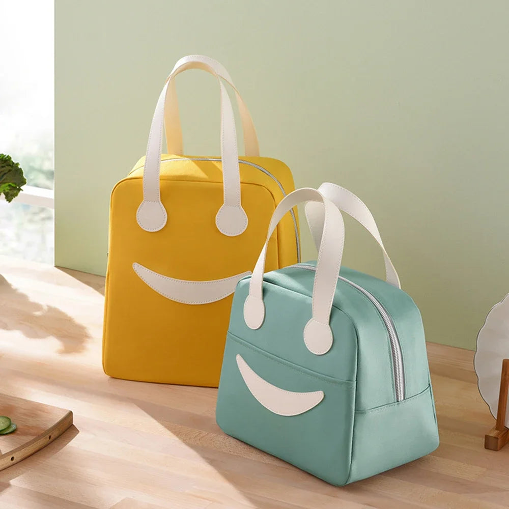 Two kawaii lunch bags, one yellow and one green, with smiley face designs on a wooden surface.