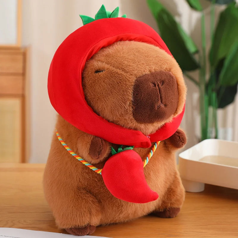 Kawaii plush toy dog wearing a red chili pepper costume on a wooden surface.