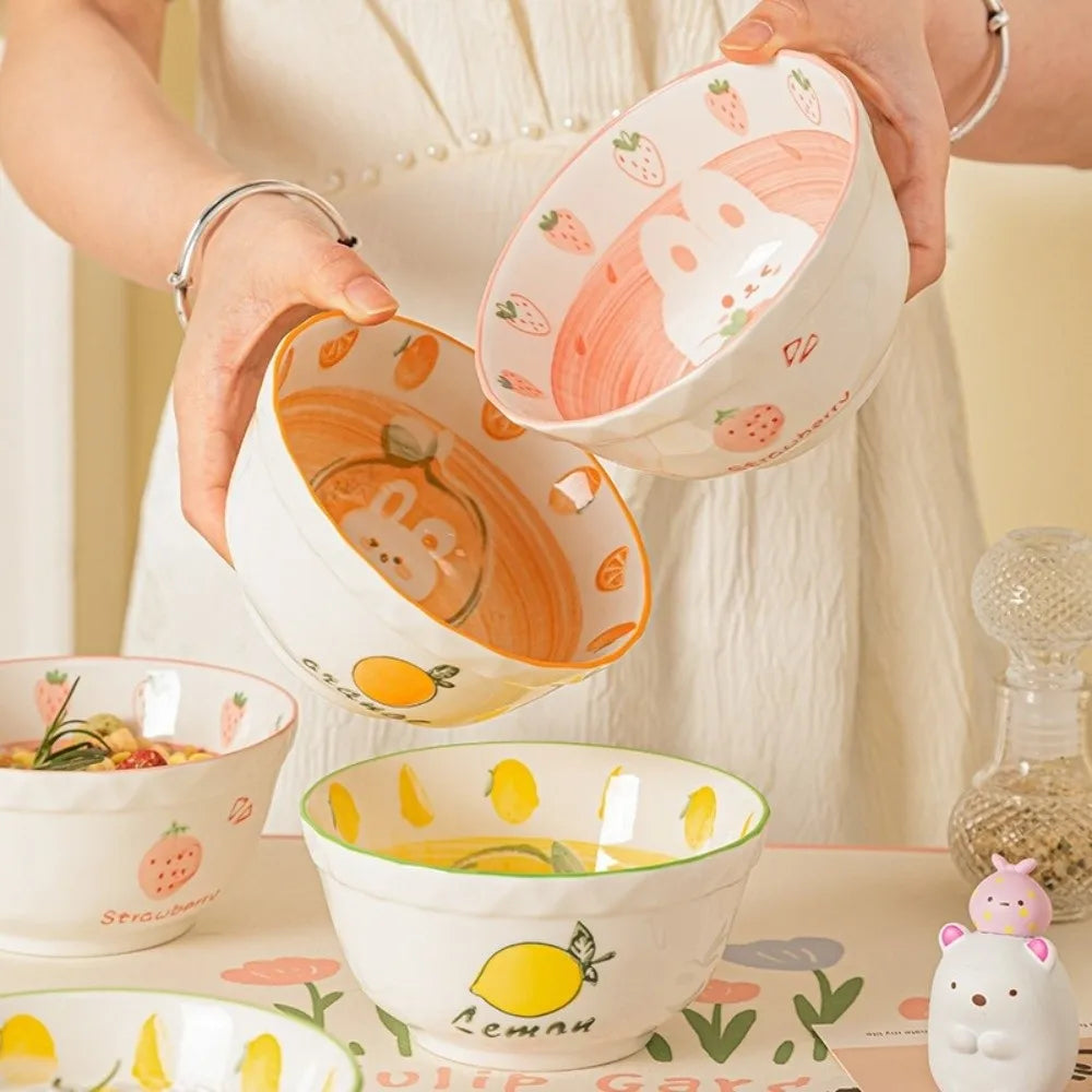 Set of colorful ceramic kawaii ramen bowls with fruit patterns on a table.