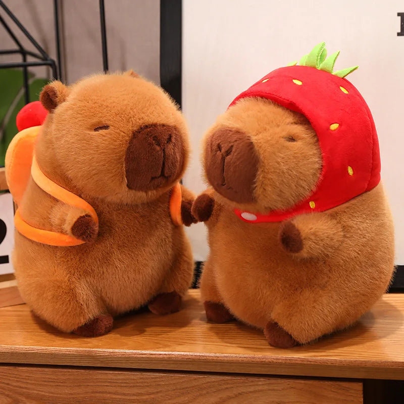 Two kawaii plush toys resembling beavers, one with an orange scarf and the other with a strawberry hat, on a wooden surface.